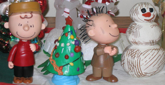 peanuts figurines are standing in front of a christmas tree