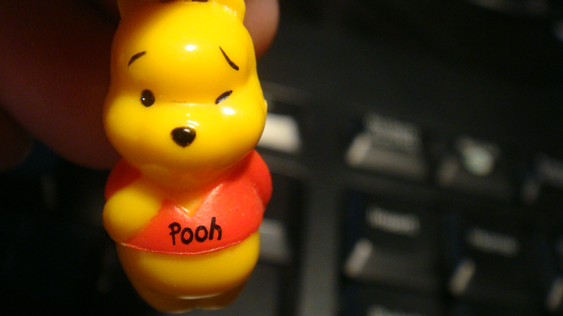a yellow winnie the pooh key chain attached to a keyboard