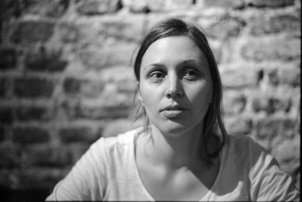 woman looking at camera while sitting down against a brick wall