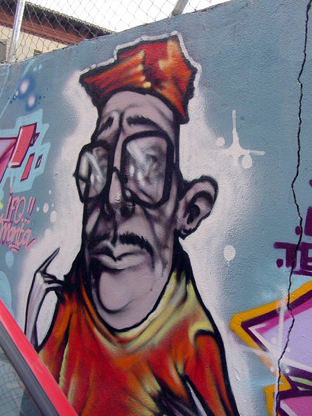 a wall with graffiti that has a man wearing a hat on it