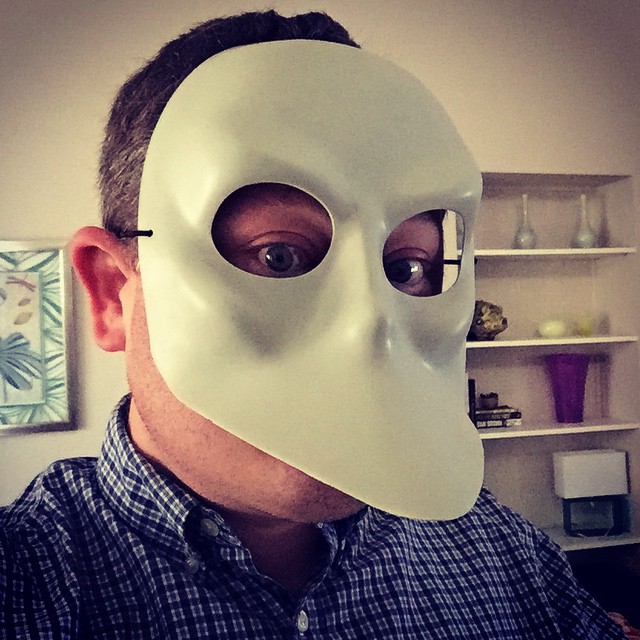 a man in shirt and mask is holding onto white object