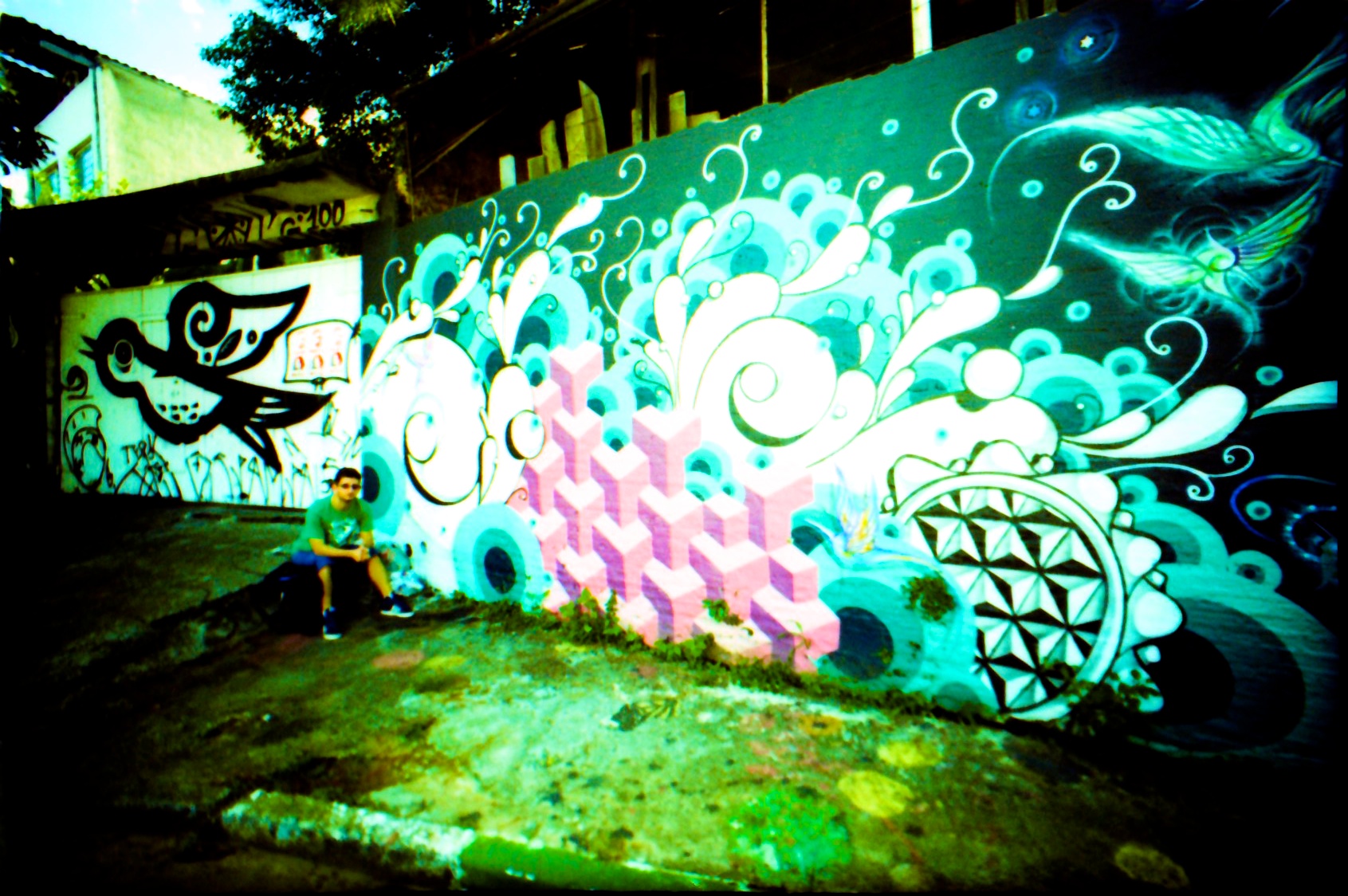 the man is sitting by a wall that has been painted with many colors