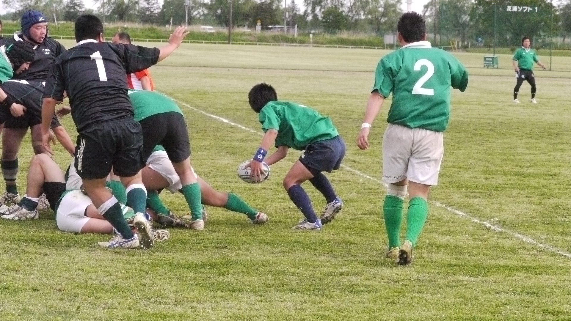 several boys playing rugby on a green field