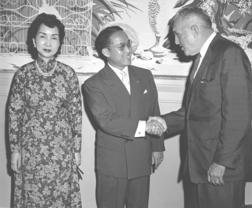 two men and one woman shaking hands at a ceremony