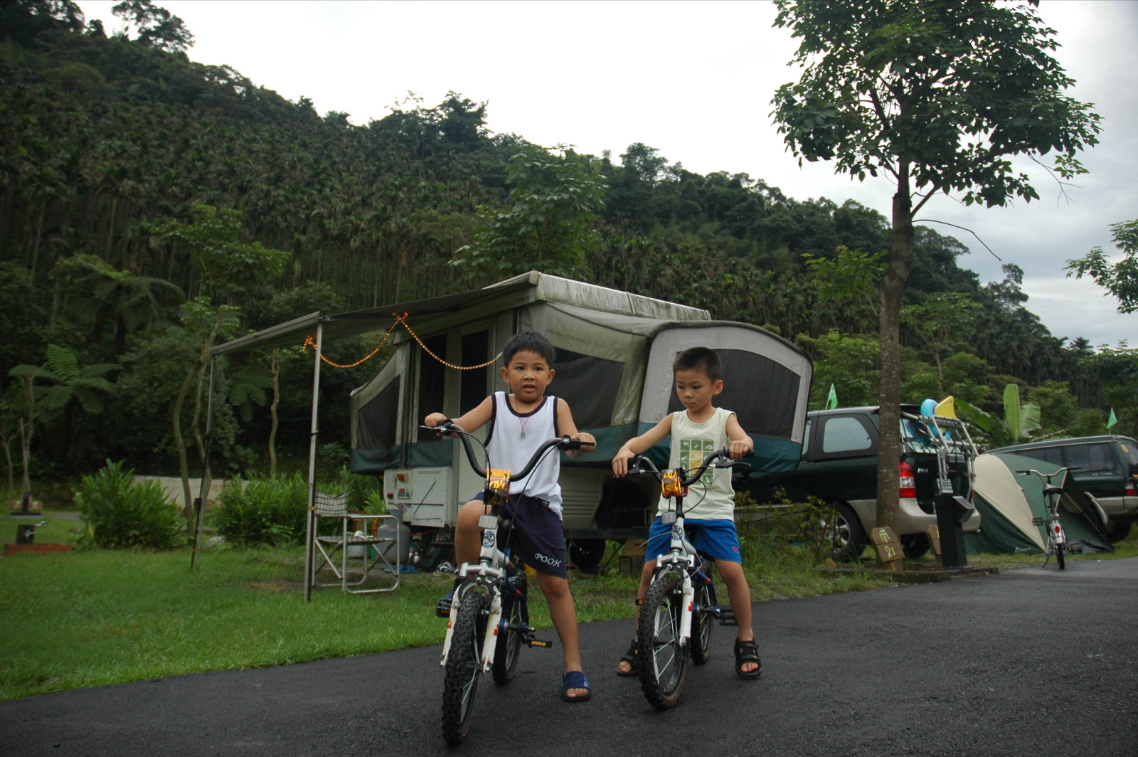 two boys riding bikes next to a mobile home