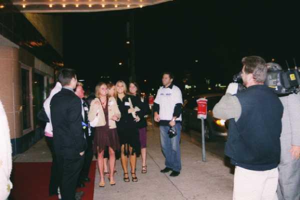 a bunch of people on the sidewalk near a couple of cars