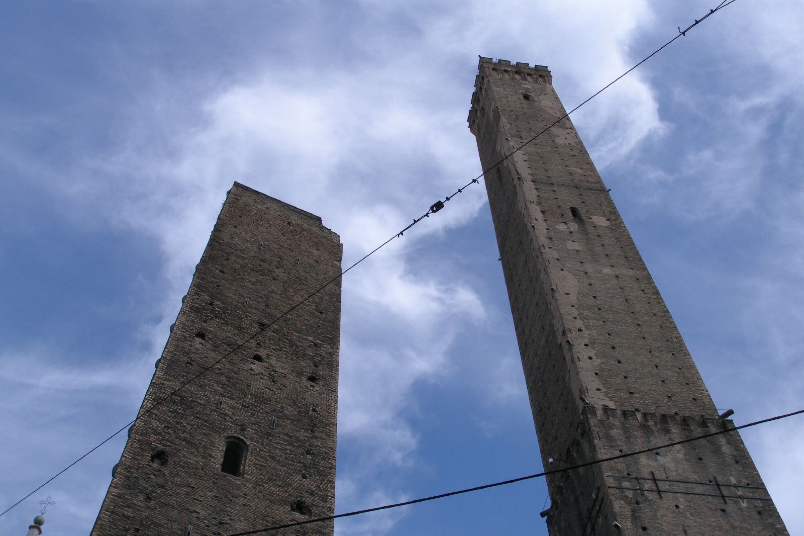 two tall brick buildings in the air, with power lines behind