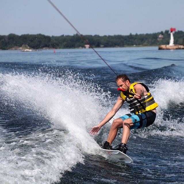 a person on a wakeboard rides water with trees in the background