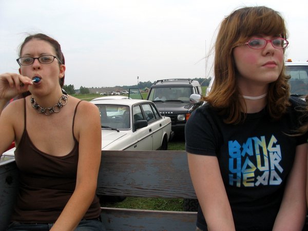 two woman sitting on a bench with cars in the background
