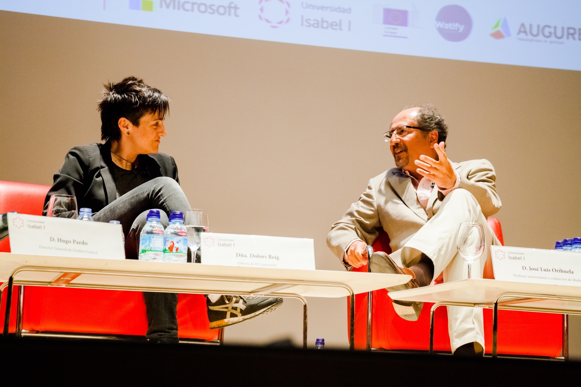 two people at a table during a seminar with microphones