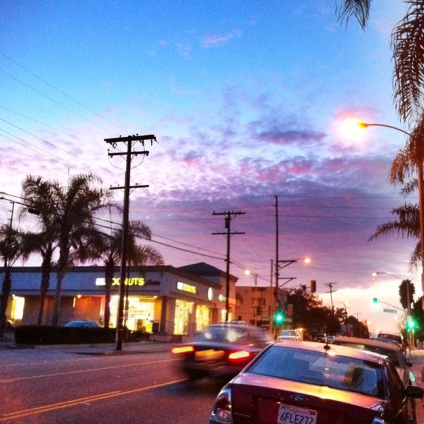 a small car drives through the street with the sunset in the background