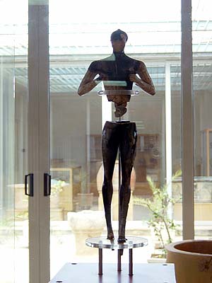 a mannequin stands on a stand near some flowers