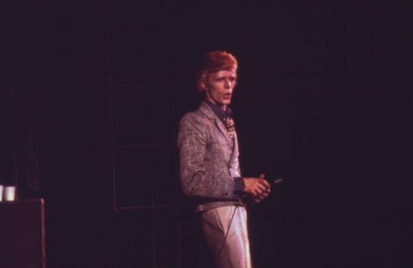 a man stands on stage and holds a cell phone