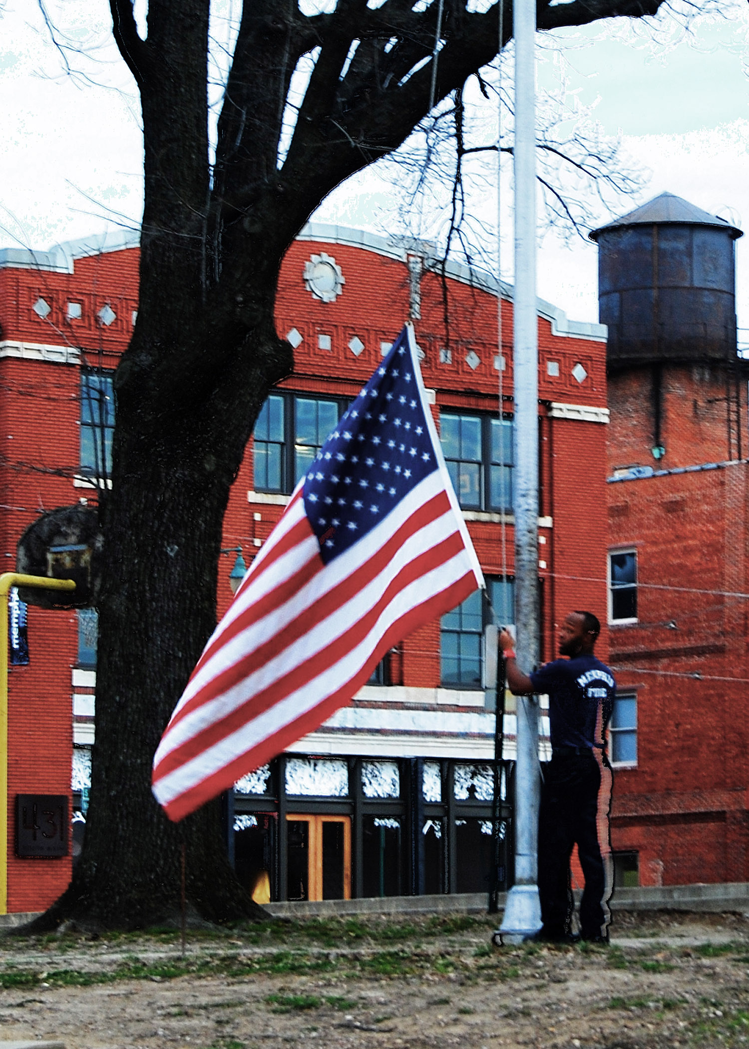 an american flag being held up in front of a firehouse