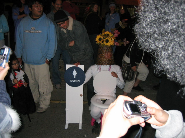 the people stand around a toilet on display