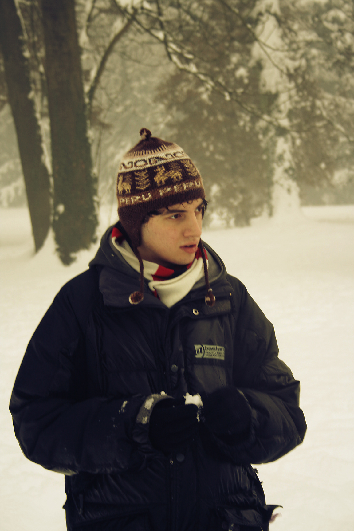 boy in a winter hat and coat standing in snow