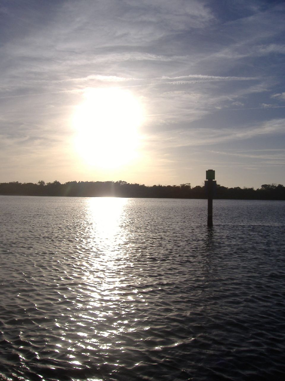 a body of water with some clouds and a sun