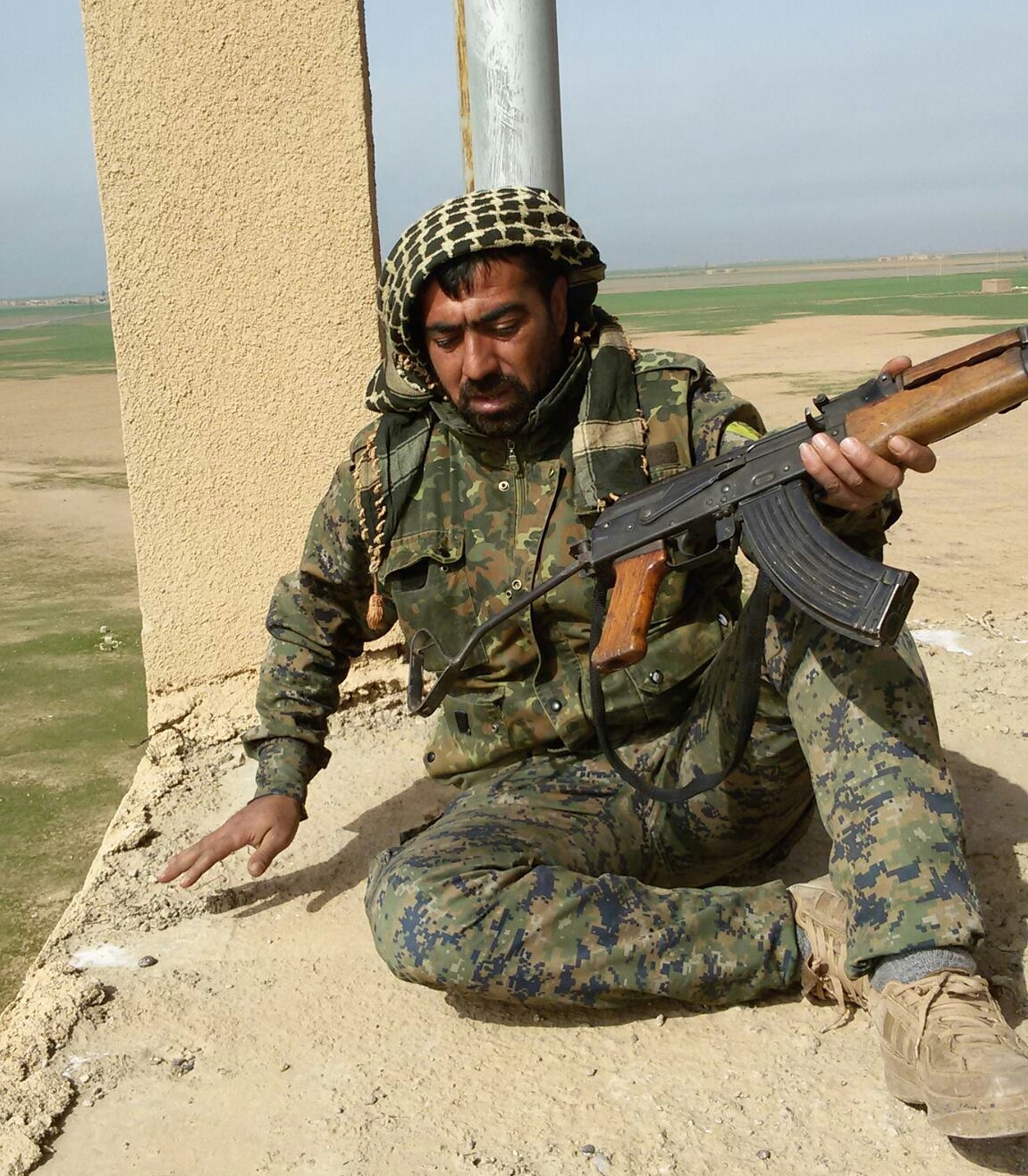 a man with a gun sitting on the ground