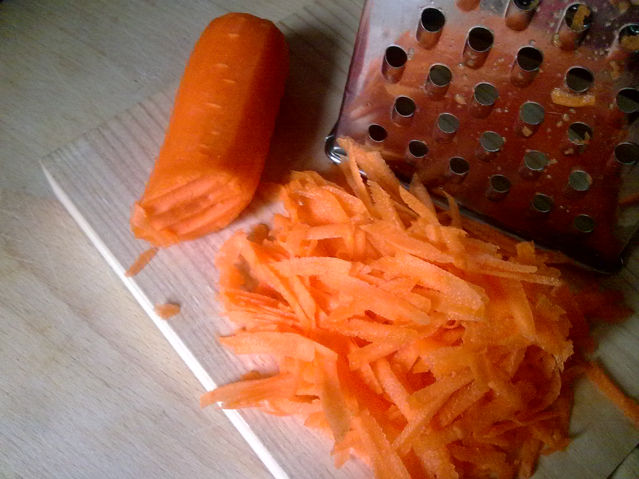 an image of carrots and grater on a  board