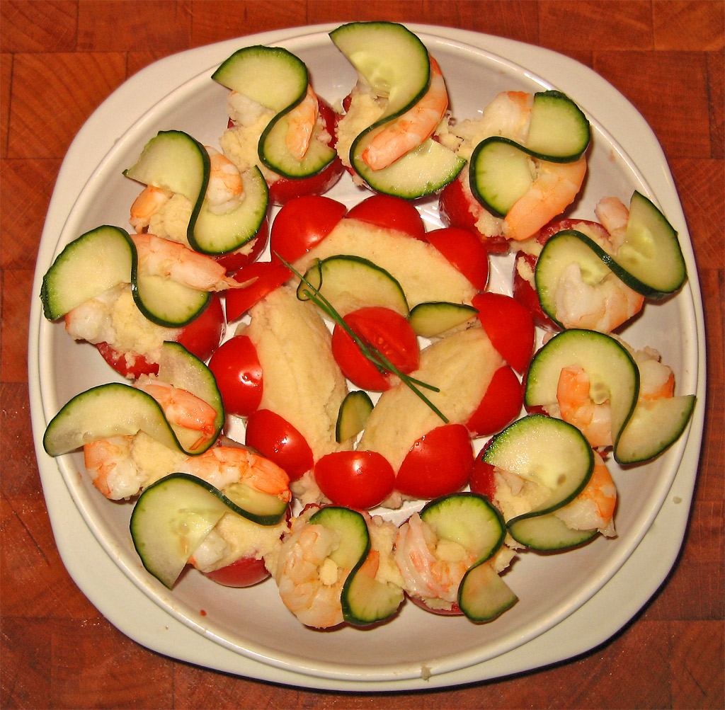 a plate with shrimp, zucchini and tomato slices