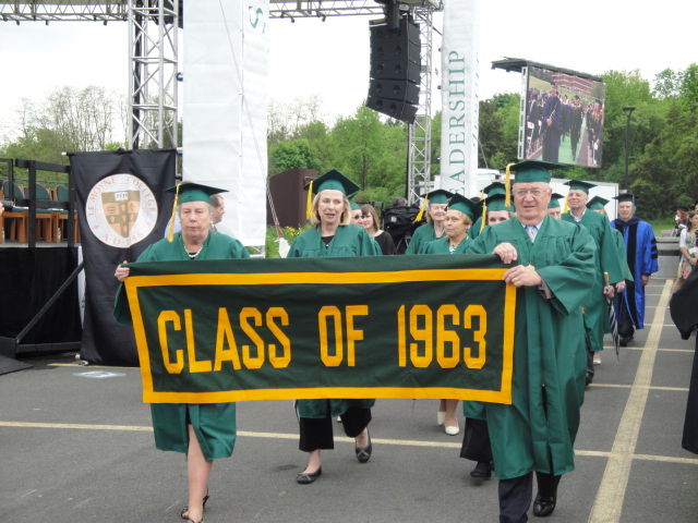 students in graduation gowns carrying a banner at graduation