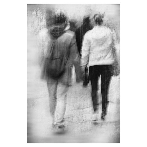 the back of two people walking on a city street