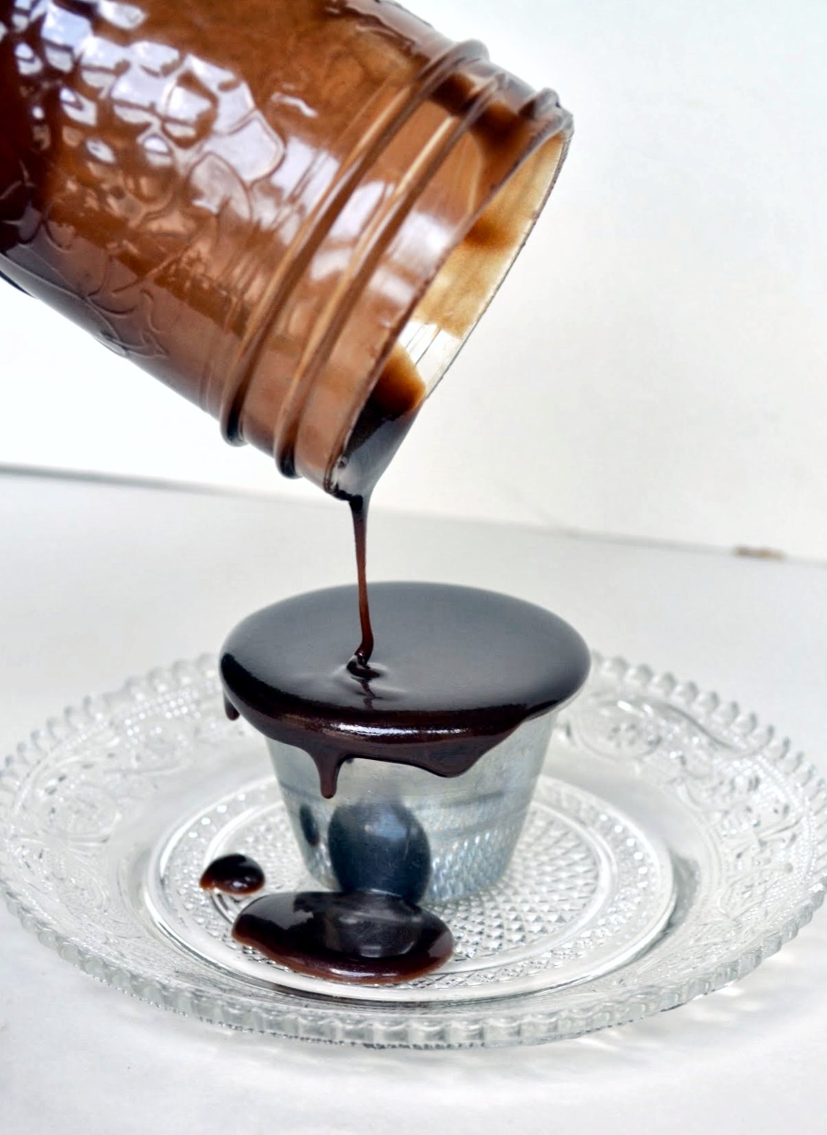 a glass plate with chocolate on it and a bottle being poured into the cup