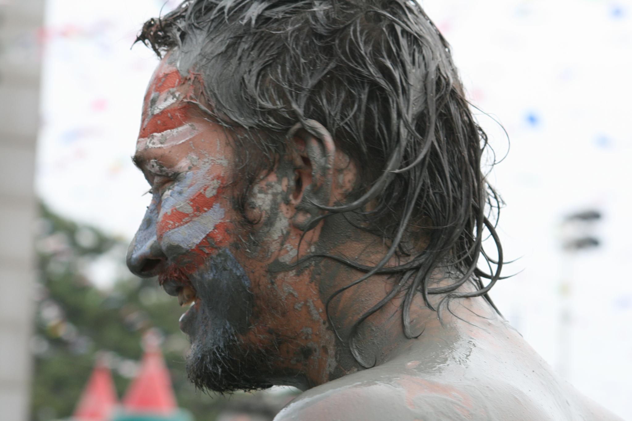 the face of a man covered in white and red, with his hair pulled back