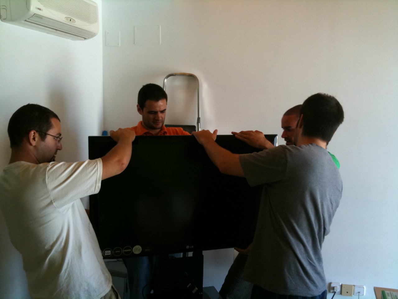 three men standing in front of a computer screen