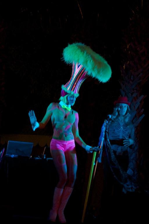 a woman with a feather top standing on stage in neon outfit