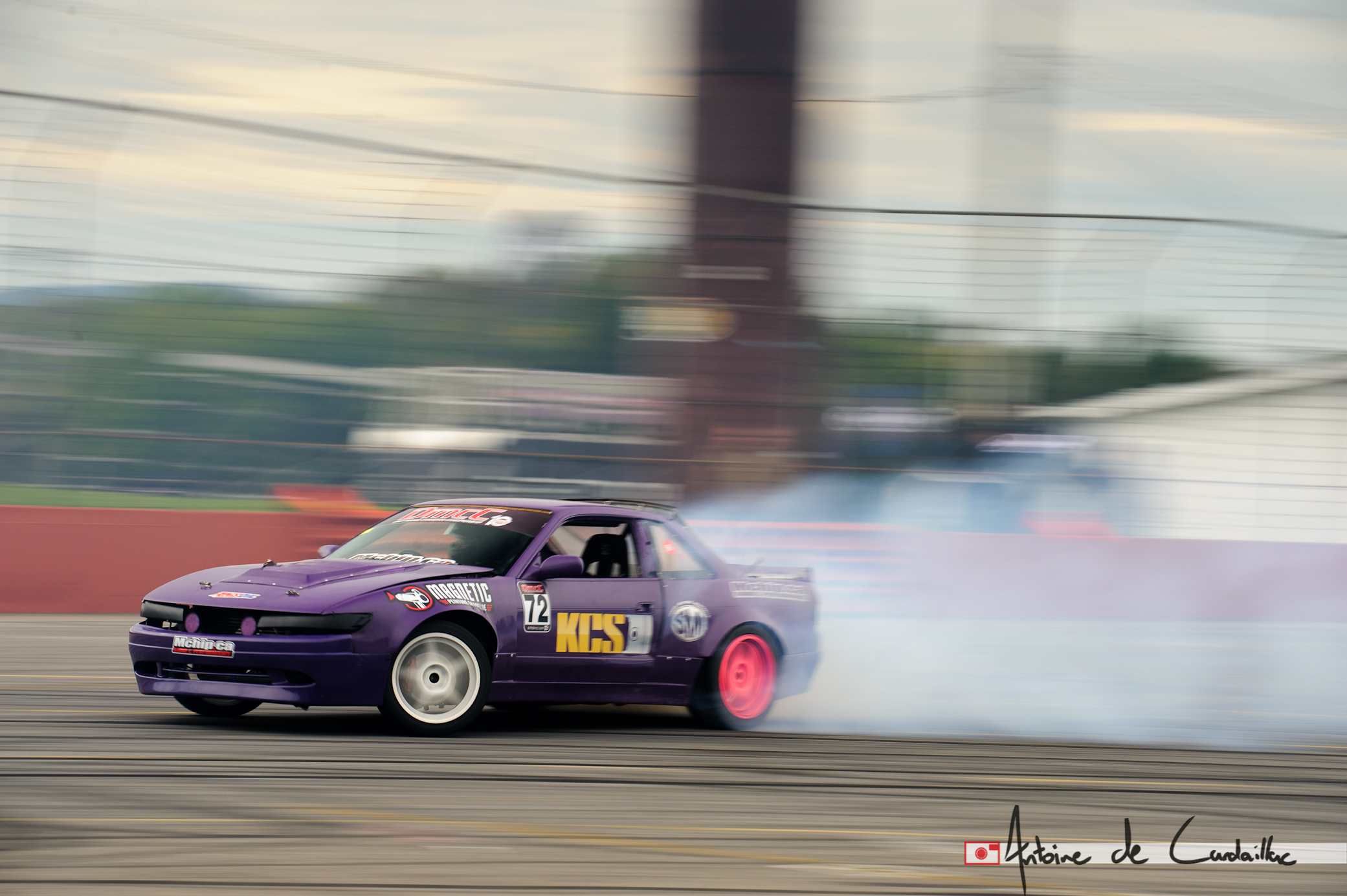 a small car spins around a track with smoke coming out of it