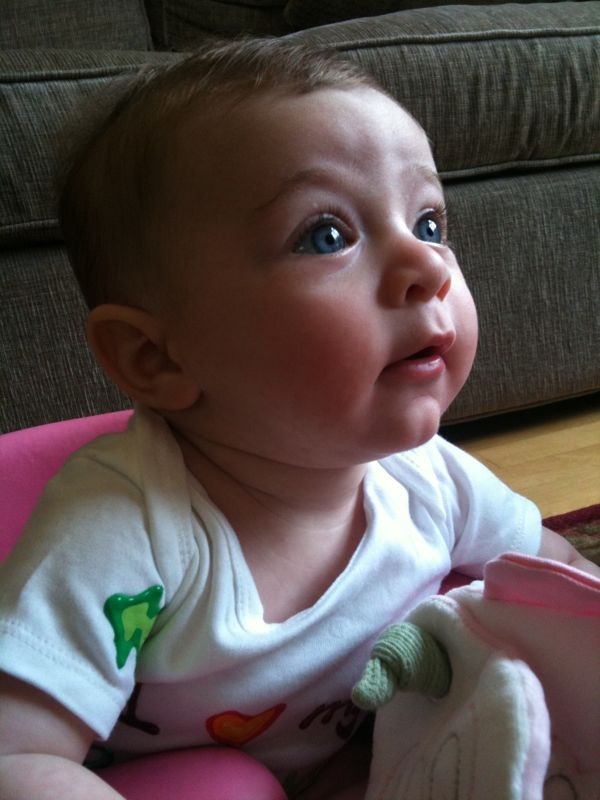 a young baby sitting in a pink chair on a rug