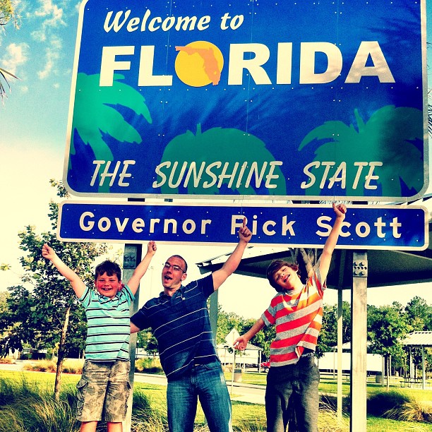 three men standing in front of a welcome sign