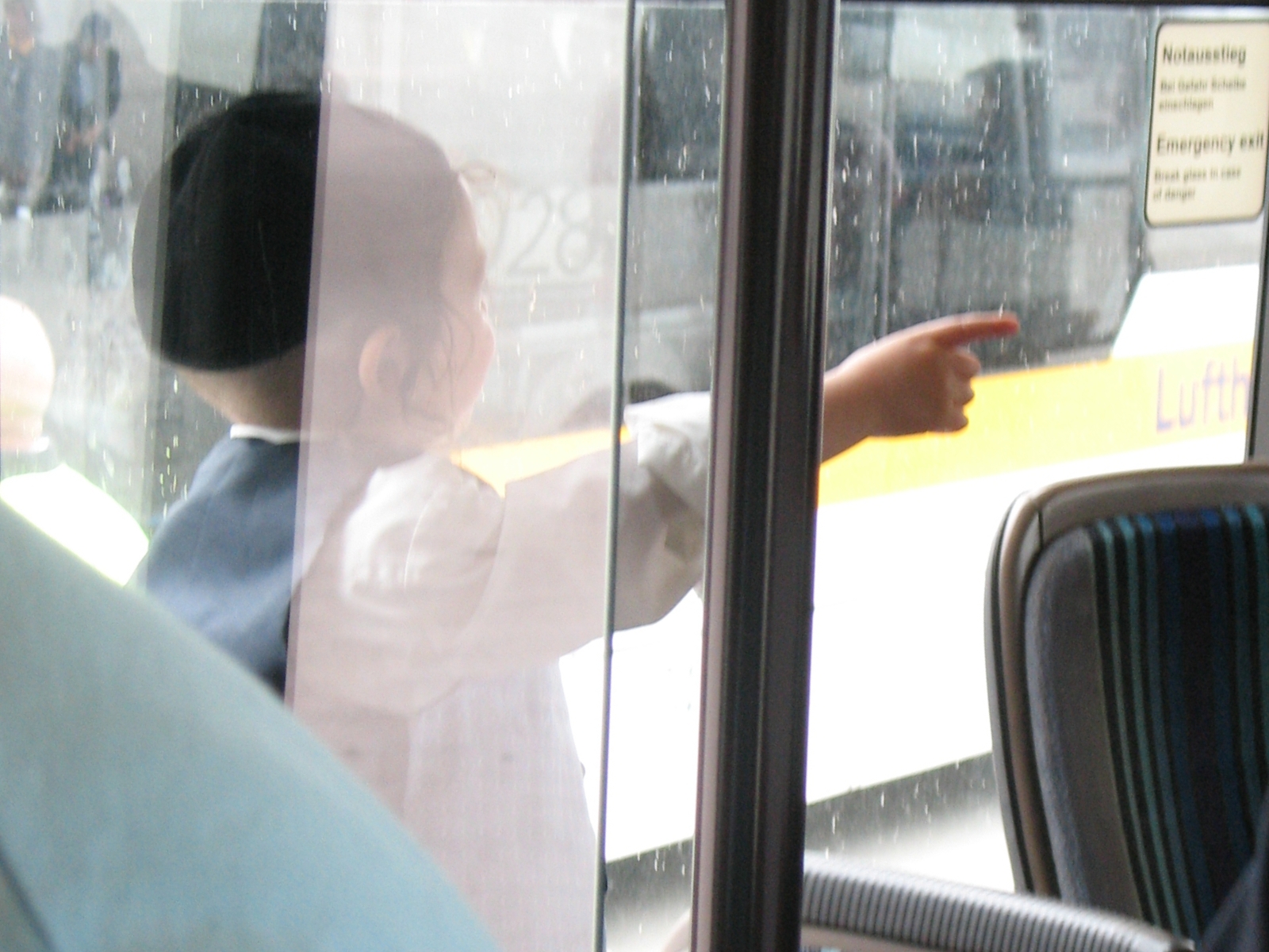 a child sitting in the seat of a bus pointing at soing