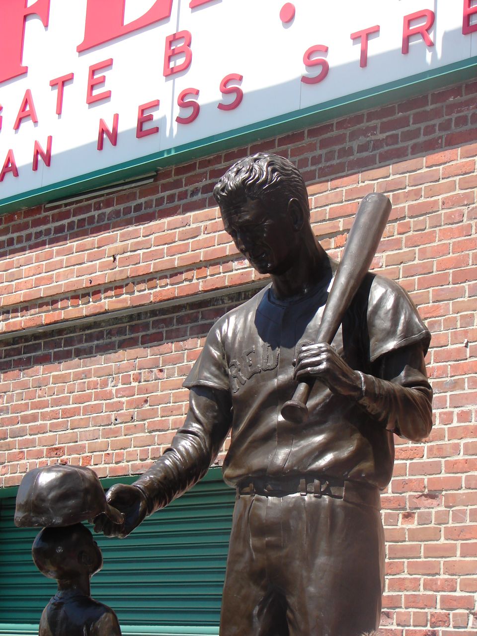 a statue of a baseball player holding a bat next to a child