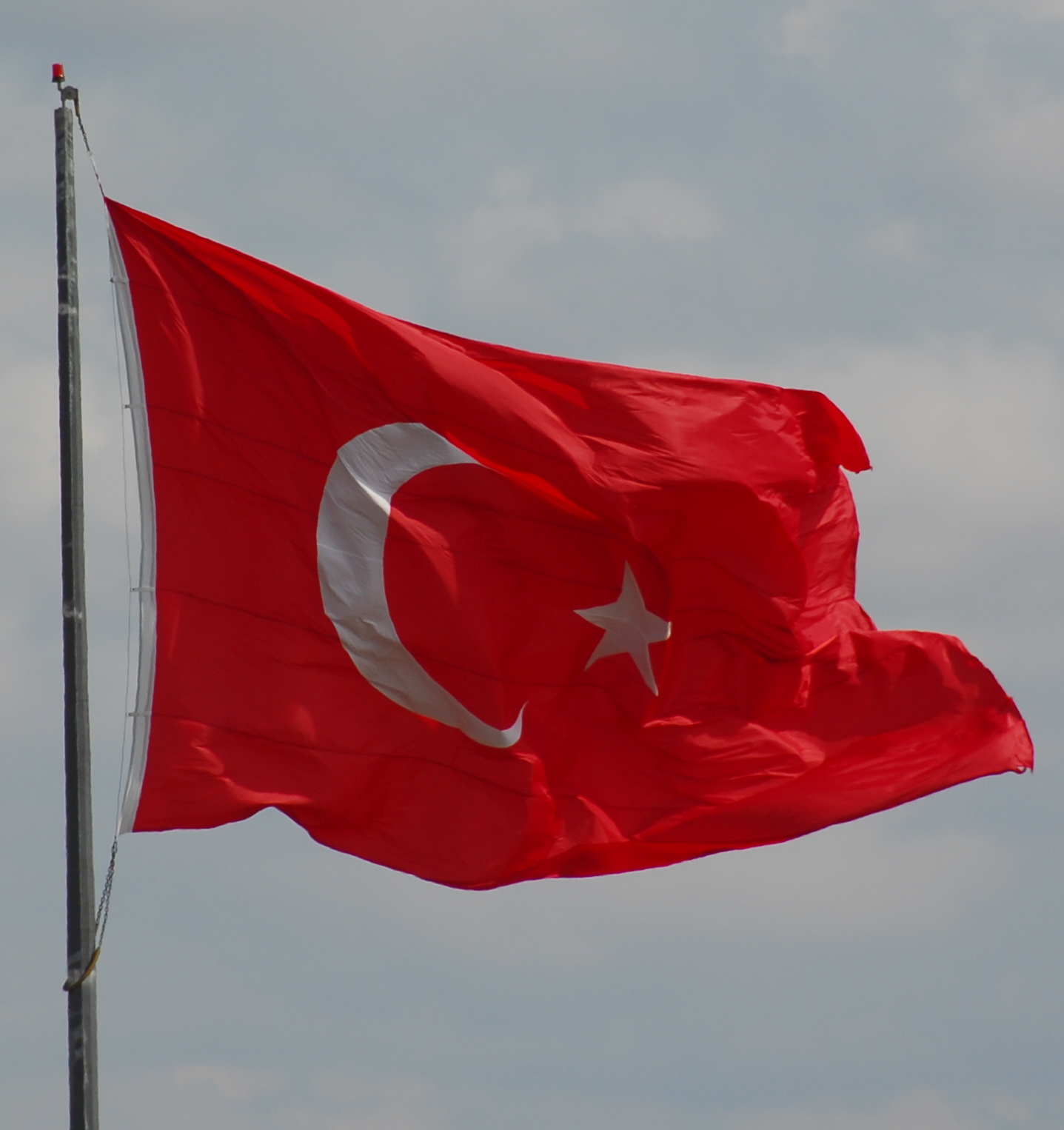 the turkish flag is flying in front of a cloudy sky