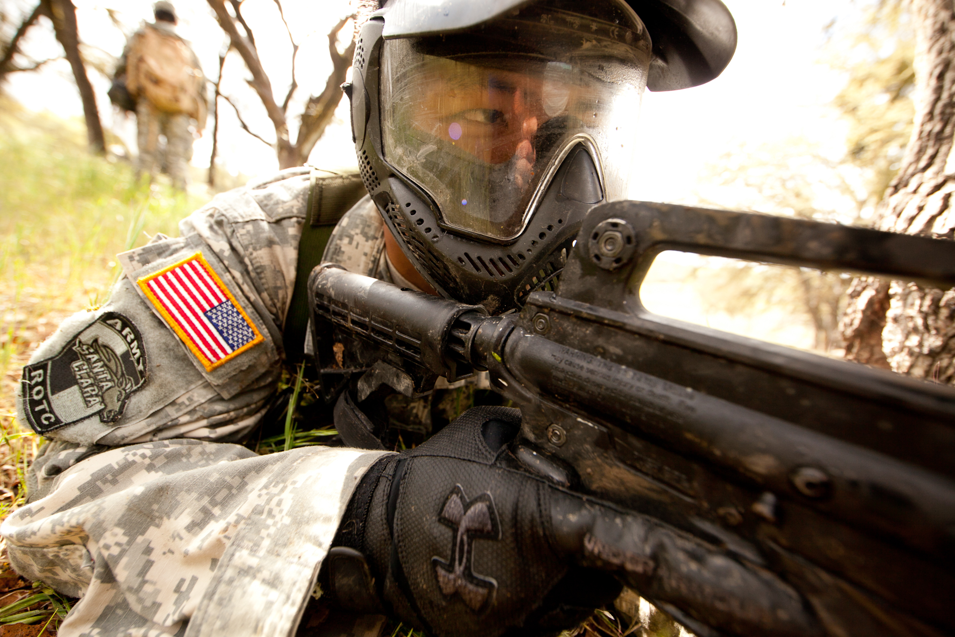 a man wearing military uniform in the woods with an american flag on his helmet and goggles