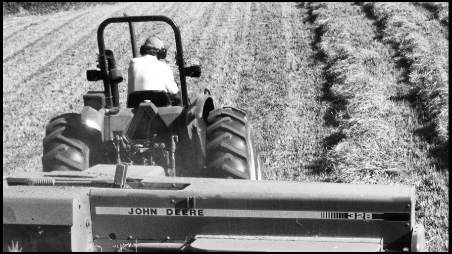 black and white pograph of tractor with owner driving