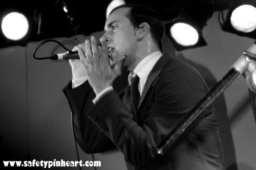 black and white pograph of man singing into microphone in public