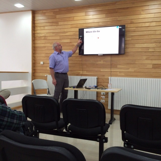 a man giving a lecture on the television screen in an office