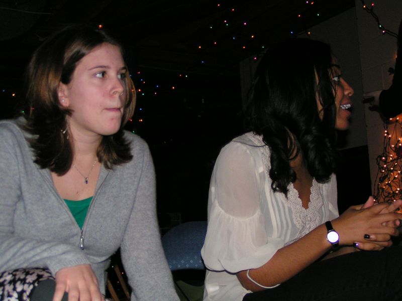 two women sit at the front of a table while staring into the distance