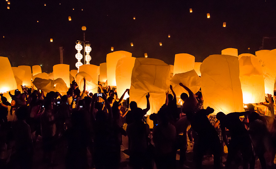 many people are flying lanterns at night time
