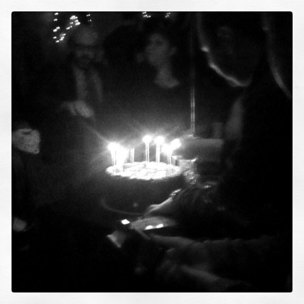 a cake with lit candles sits in front of several people