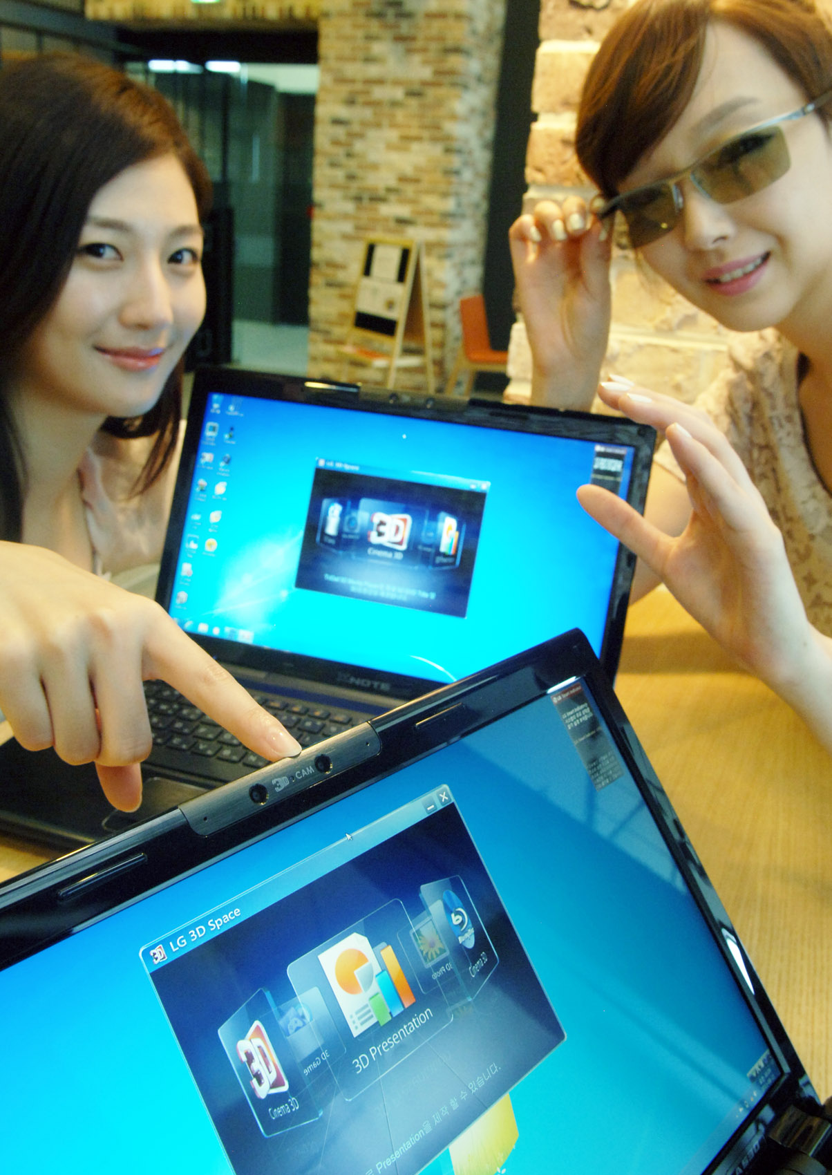 two women, one in glasses on their computers are smiling at the camera