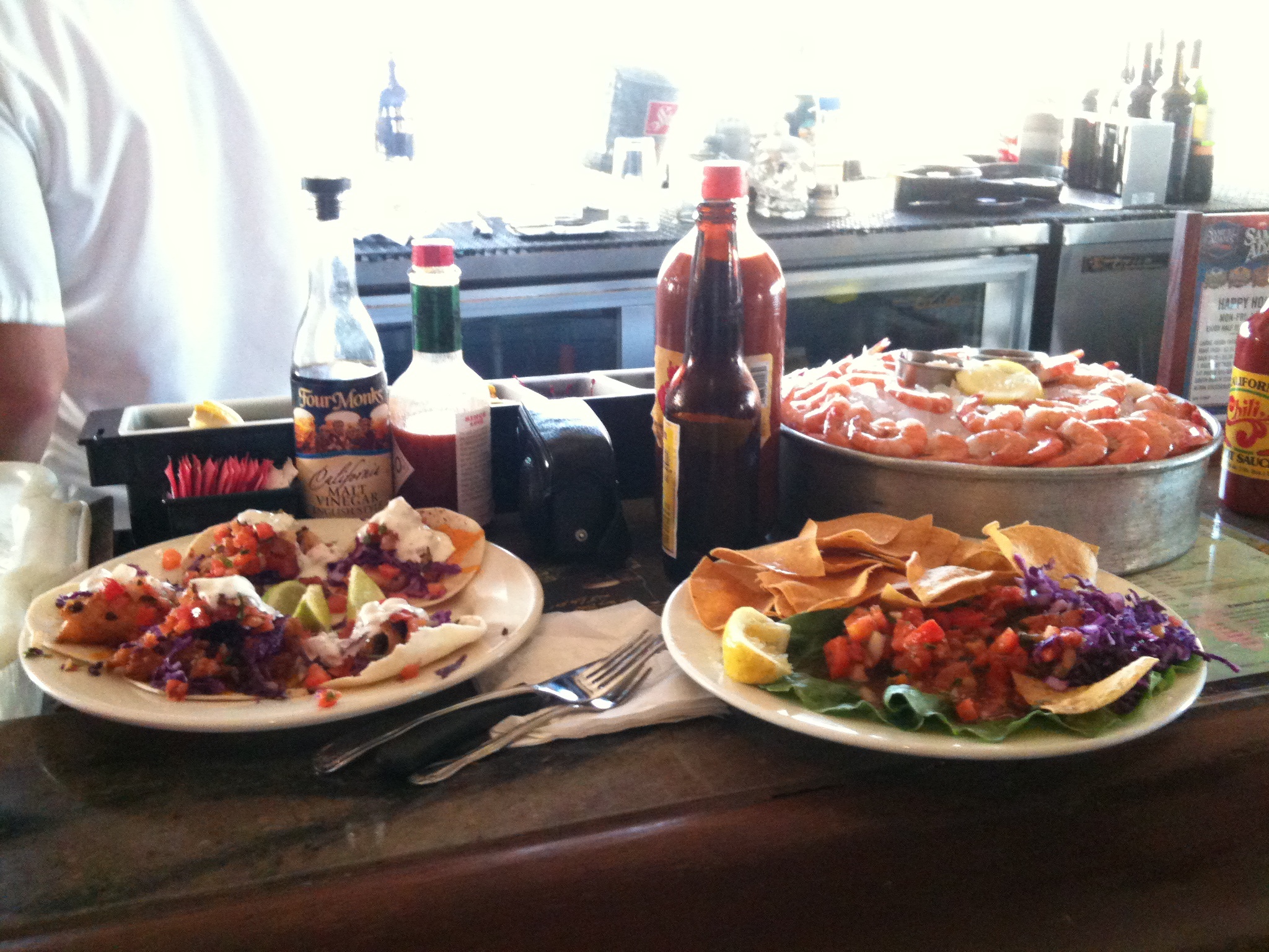 two plates with food on them and bottles near by