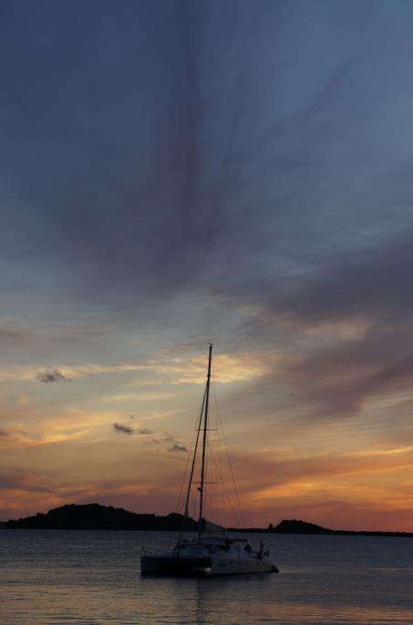 a sailboat anchored on a body of water at sunset