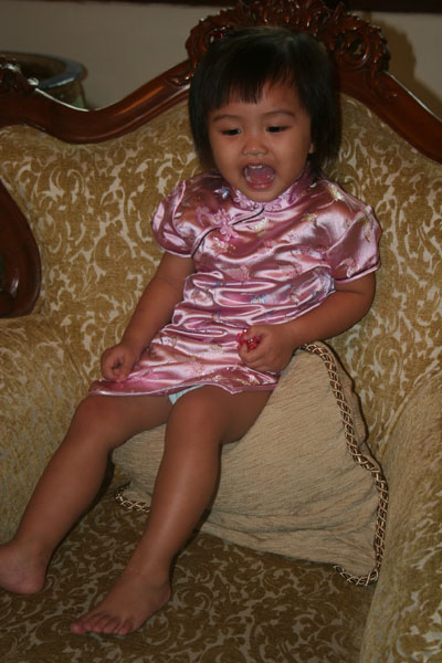 a toddler sitting on a brown chair and smiling