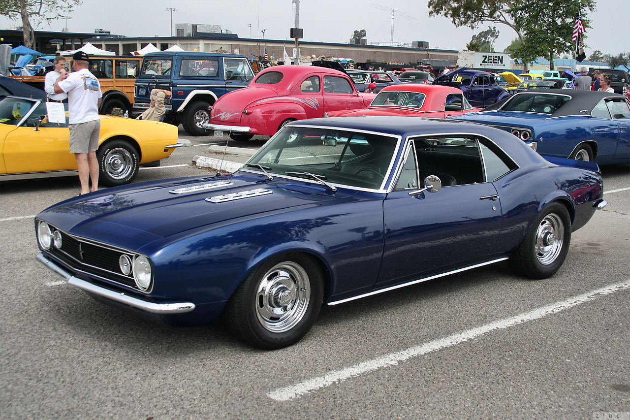 a blue sports car sits in the parking lot with others