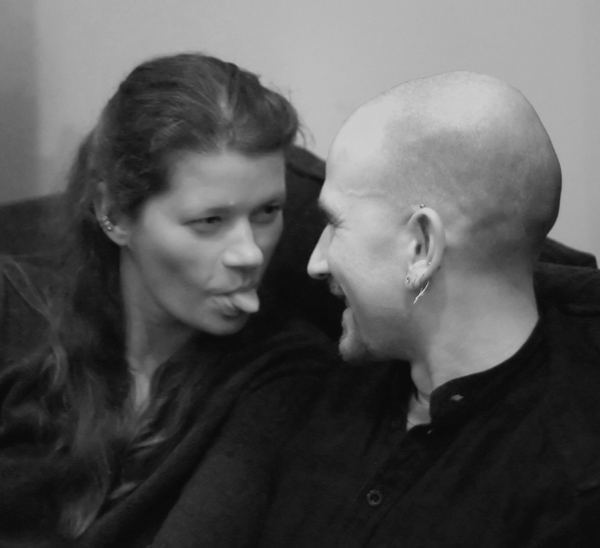 an image of a bald man and woman sticking their tongues out