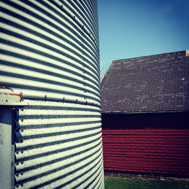 an outside view of a metal tank with a red barn in the background